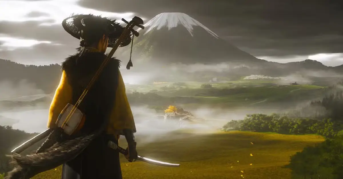 A protagonista de Ghost of Yōtei, Atsu, em pé num campo de erva alta a olhar para o Monte Yōtei